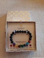 Complete view of chakra gemstone bracelet in decorative box with chakra colors and description