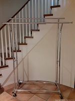 Front view of the metal double clothing rack showing two horizontal hanging bars and caster wheels.