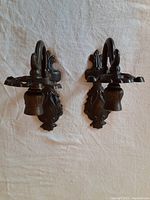 Pair of bronze candle sconces laid flat showing front view and details of the design.