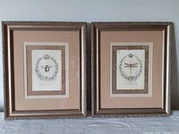 Pair of framed Kathryn White prints Abeille and Libellule on a flat surface.