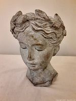 Front view of the lady's head cement planter showing facial details and leaf crown