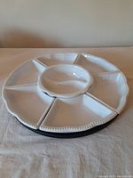 Top view of the white ceramic Lazy Susan with six segmented trays and center bowl on a wooden base.