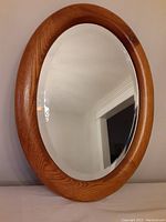 Front view of oval bevelled mirror with solid oak frame showing reflective surface and wood grain.