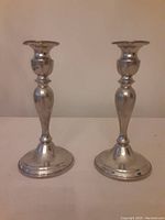 Front view of the pair of pewter candlesticks standing side by side showing overall shape and finish