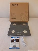 RENPHO ES-30M Smart Scale with box, scale, USB cable and guide on white surface.
