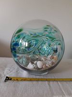 Front view of clear glass seashell globe showing interior seashells and colored swirls