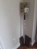 Photo showing three solid oak hardwood vent covers placed against a wall corner and the Bayco SAFE-N-EZY Bulb Gripper in packaging with an extendable pole.