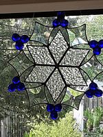 Front view of snowflake stained glass panel showing clear bevelled glass and clusters of blue cabochon glass tips.