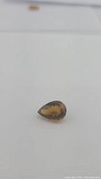 Pear shaped Madeira citrine gemstone with deep whiskey color on a plain background super close up.