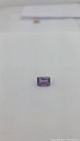Front view of deep purple emerald cut amethyst gemstone on white background