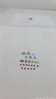 Top clear photo of 22 mixed cut natural gemstones laid out in neat rows by color and shape on white background with transparent cover above.
