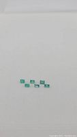 Image of six natural Columbian emeralds loose stones, arranged in a small group on white background.