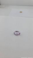 Photo showing oval cut light purple pink amethyst placed on white background, showcasing its size and clarity