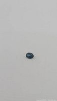 Oval-cut natural blue sapphire gemstone with deep blue color on plain background.