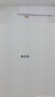Photo showing three small blue-violet round diamond cut tanzanite stones arranged horizontally on white background, showcasing their size and color.