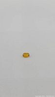 Oval cut natural golden yellow sapphire gemstone on plain white background, showing size and color