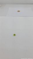 Close-up photo of the natural green peridot gemstone showing cushion cut and transparent apple green color.