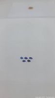 Five natural royal blue kyanite gemstones on a white surface shown from an above angle to display size and shape.