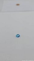 Front close-up photo of the natural Swiss blue topaz gemstone showing oval cut and vibrant blue color on a white background.