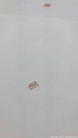 Two small watermelon tourmaline gemstones placed on white background. Stones are baguette cut with pastel pink and green colors.