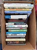 Photo of a first stack of books including crafting, dictionaries, sports, self-help, and cookbooks.