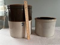 Two ceramic crocks side by side with wooden ruler for scale.