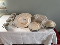 Wide view of the full dish set for four with mugs, bowls, plates, and saucers displayed on a white tablecloth.