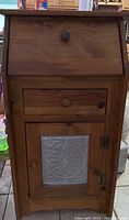 Closed view of the wooden pie safe cabinet showing the front door with embossed tin panel and drawer above it.