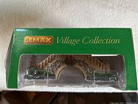 Lemax Village Collection green box with stone arch bridge, stairs, Christmas decorations, and small Christmas tree
