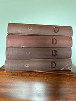 Stack of four brown record albums labeled E, D, C, B with metal ring pulls on spines used for holding Victor Victrola records.