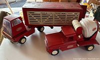 Red Tonka semi-truck with removable livestock trailer and red cement mixer truck with white drum, showing front and side detail.