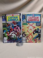Two comic books with colorful front covers featuring Captain America, parts 5 and 6 of the Bloodstone series, bagged and boarded.