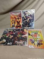 Full view of all 5 Phoenix Resurrection comics arranged on a fabric surface, showing various covers with Jean Grey and Phoenix themes.