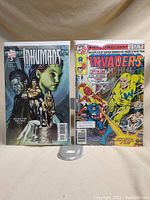 Two comics displayed: Marvel Inhumans #12 on the left, Marvel Invaders on the right. Both bagged and boarded.