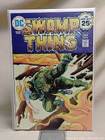 Front cover of Swamp Thing #14 comic book showing title, cover art with Swamp Thing character amid flames and rescue scene, and publishing details.