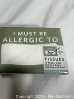 Close-up photo showing the front of a single pack of tissue with packaging featuring the text 'I MUST BE ALLERGIC TO' and measurement details.