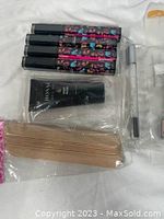 Close-up photo of four bottles of gel polish with colorful patterned labels, a black nail file, and wooden nail sticks.