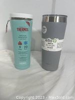 Thermos and Ello insulated bottles standing side by side, visible branding and labels.
