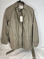 Full front view of taupe faux leather anorak jacket for women, medium size, hanging on black hanger.