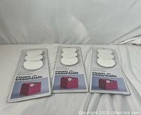 Three sealed packages of Room Essentials clip-on plastic dry erase fabric bin labels, each package containing 3 white oval labels attached on a card with branding and instructions.