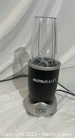 Full view of NutriBullet Magic Bullet blender with the clear blending cup attached on the base, showing the blade inside the cup.