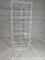 Full view of rotating white metal jewelry organizer stand showing all four tiers and multiple hooks for hanging jewelry.