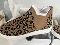 Side view of single sneaker boot showing brown and black leopard print knit fabric upper with elastic side panel and white sole.