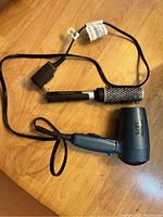 Blue BaByliss 1875 hair dryer and vented round styling brush on wooden surface.