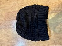 Black ribbed knit beanie showing knit pattern and leather tag