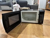 Front view of the microwave oven with the door open showing the interior and keypad.