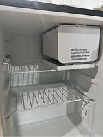 Interior view showing two wire shelves and a plastic ice compartment with ice tray at top inside the fridge.