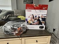 Canon PIXMA TS5320 printer original box and accessories in plastic bag on table