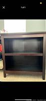 Front view of small wooden bookcase with two shelves, dark brown finish, showing condition and size