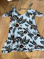 Floral cold shoulder top spread on wooden floor showing pattern and design
